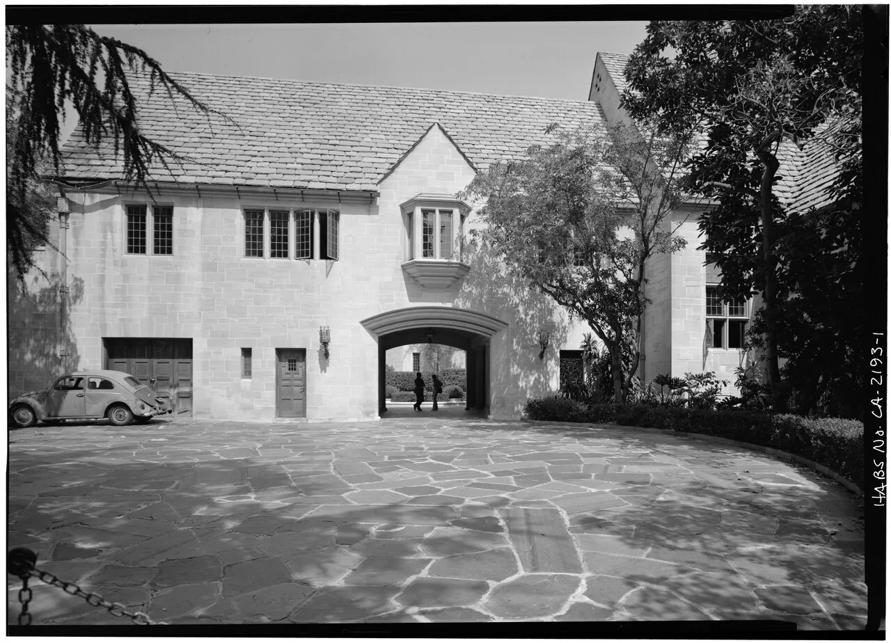 Archival photograph: the stone west entrance and flagstone forecourt of Greystone, with steep slate roofs